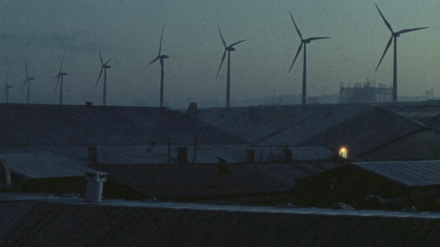 Wind turbines on the ridge beyond a UK industrial estate at first light