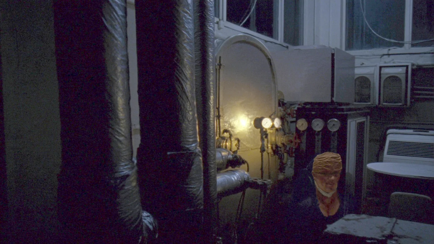 A plant room of lagged pipework and an ageing commercial gas boiler, gauges lit