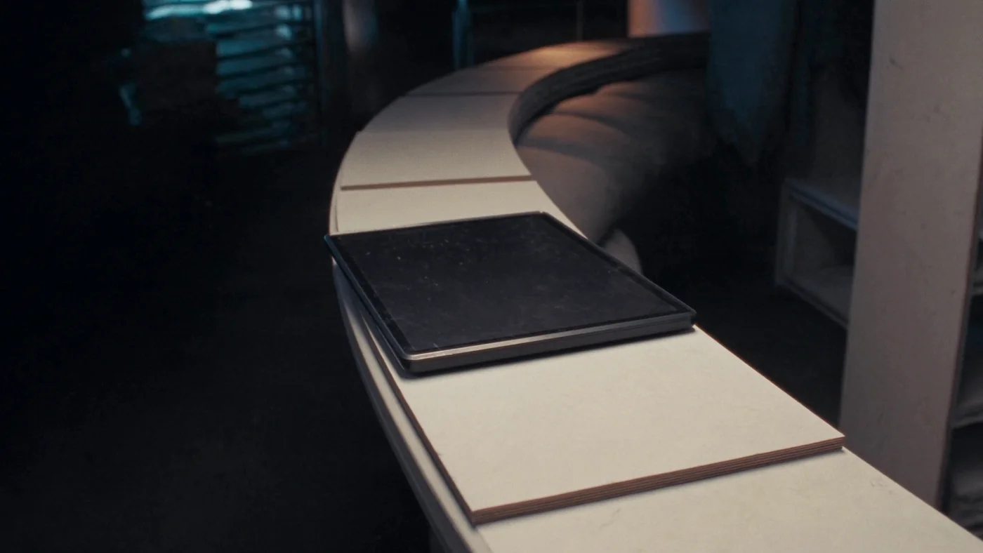 A handheld commissioning tablet resting on a plant room ledge, screen dark