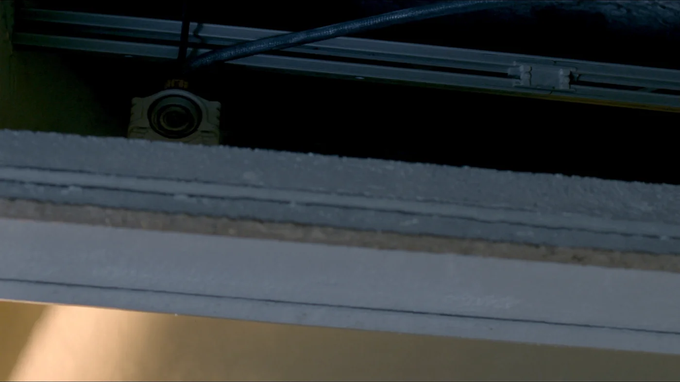 An open ceiling void showing cable trays and a sensor node