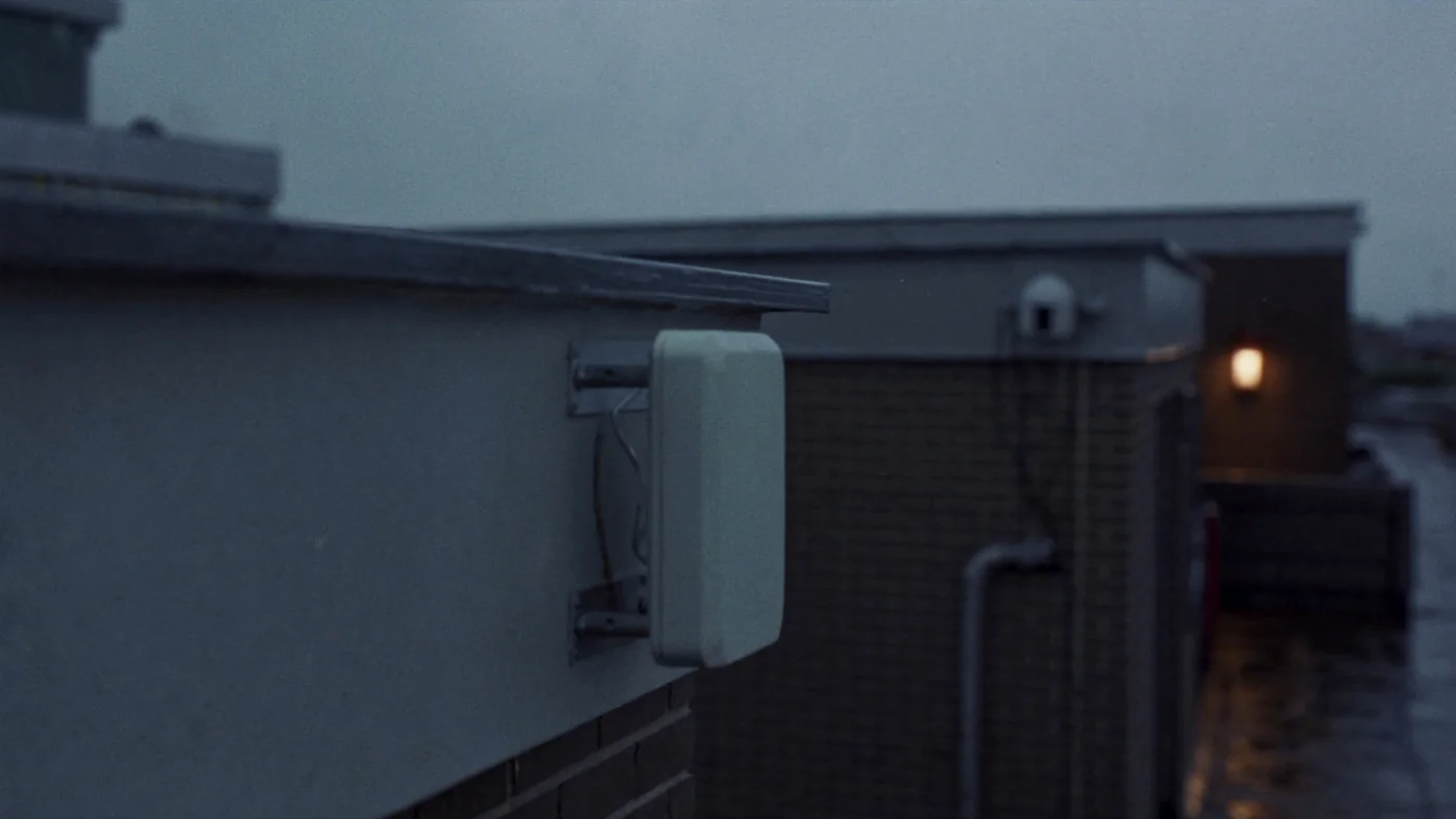 A LoRaWAN gateway antenna fixed to a rooftop parapet against an overcast sky