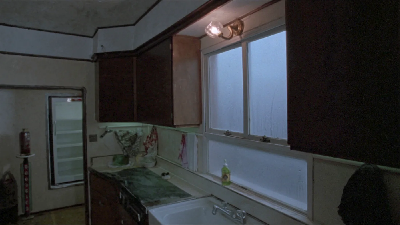 A steamed-up kitchen window above a sink, water pooling on the sill
