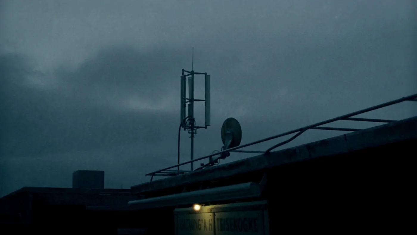 An antenna mast on a housing block roof against low cloud