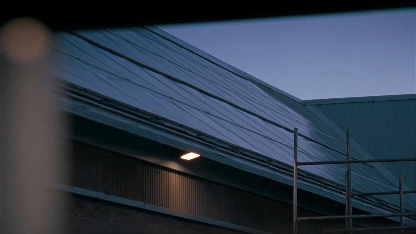 Solar panels covering the pitched roof of a UK school building at dusk