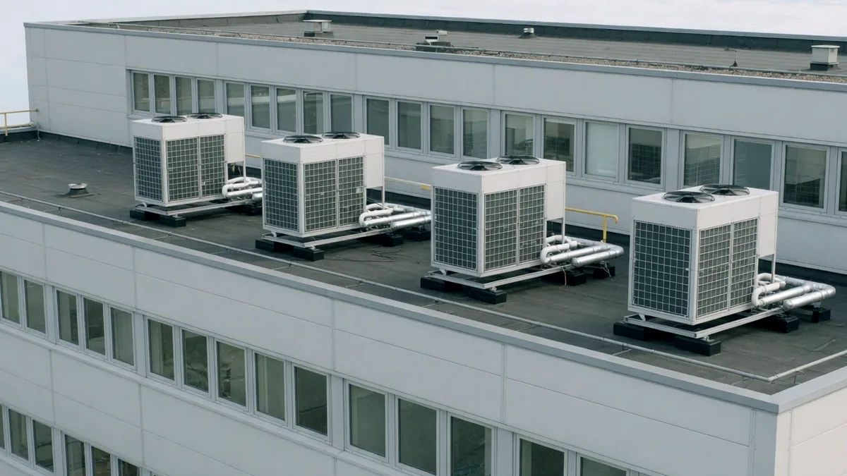 Air source heat pumps installed in a row on the roof of a modern office building