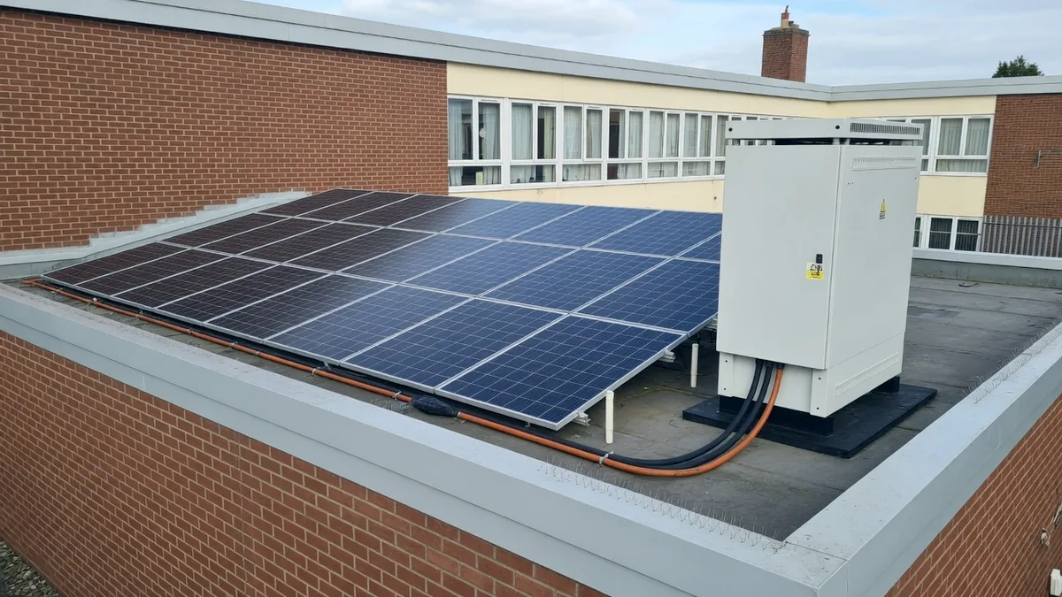 Solar panels on a school roof beside an inverter cabinet