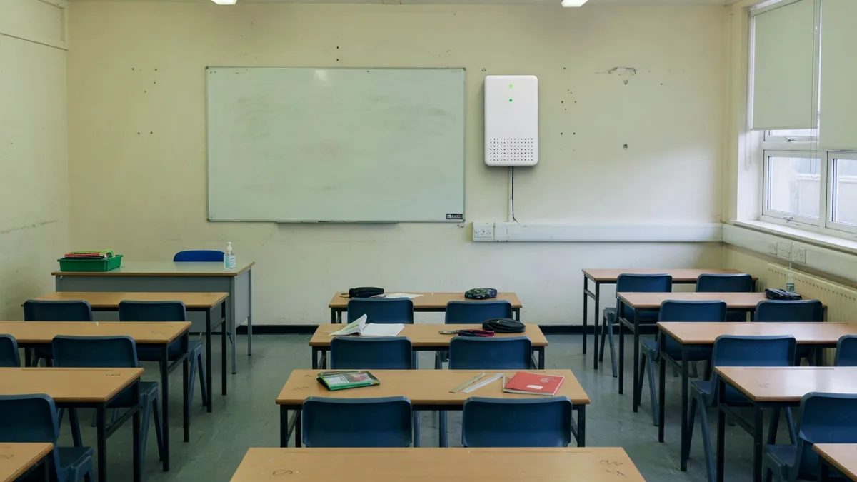 A school classroom with a small air quality sensor on the wall beside the whiteboard