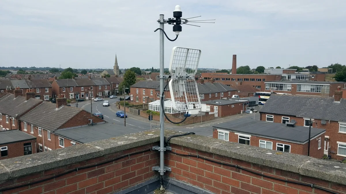 A radio gateway antenna mounted on a rooftop parapet above a town