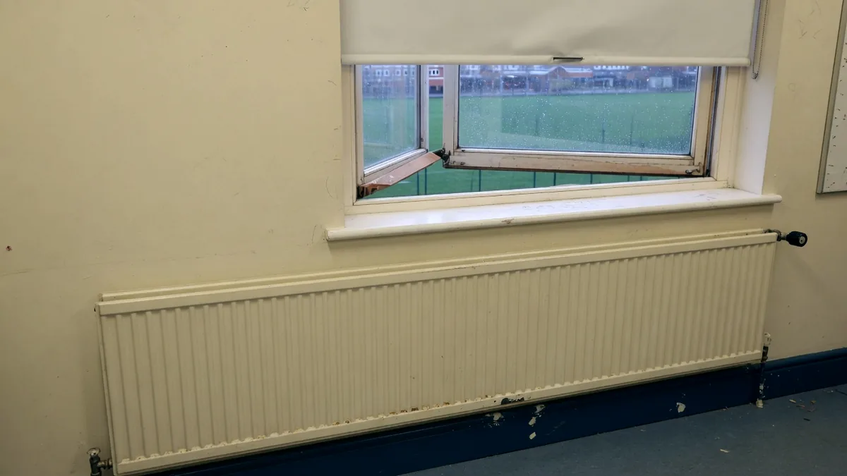 A classroom radiator running beneath a window propped wide open